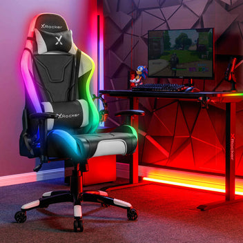 Picture of the X Rocker Agility RGB gaming chair with multi-colour LED lights in a dark gaming room aesthetic with a PC desk and computer screen