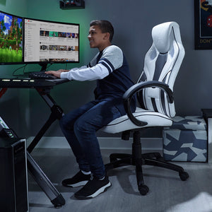 x rocker pc office gaming chair in white and black in a game room setting with LED lights and young male model sitting on the chair